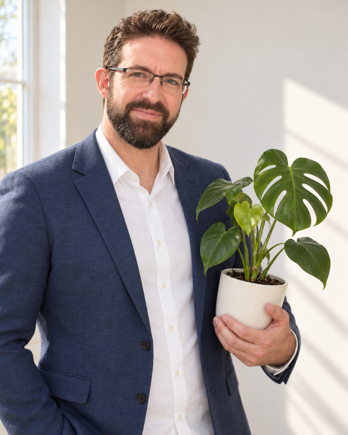 Kenneth Bannister, founder of Morning Person, holding a potted Monstera in morning light.